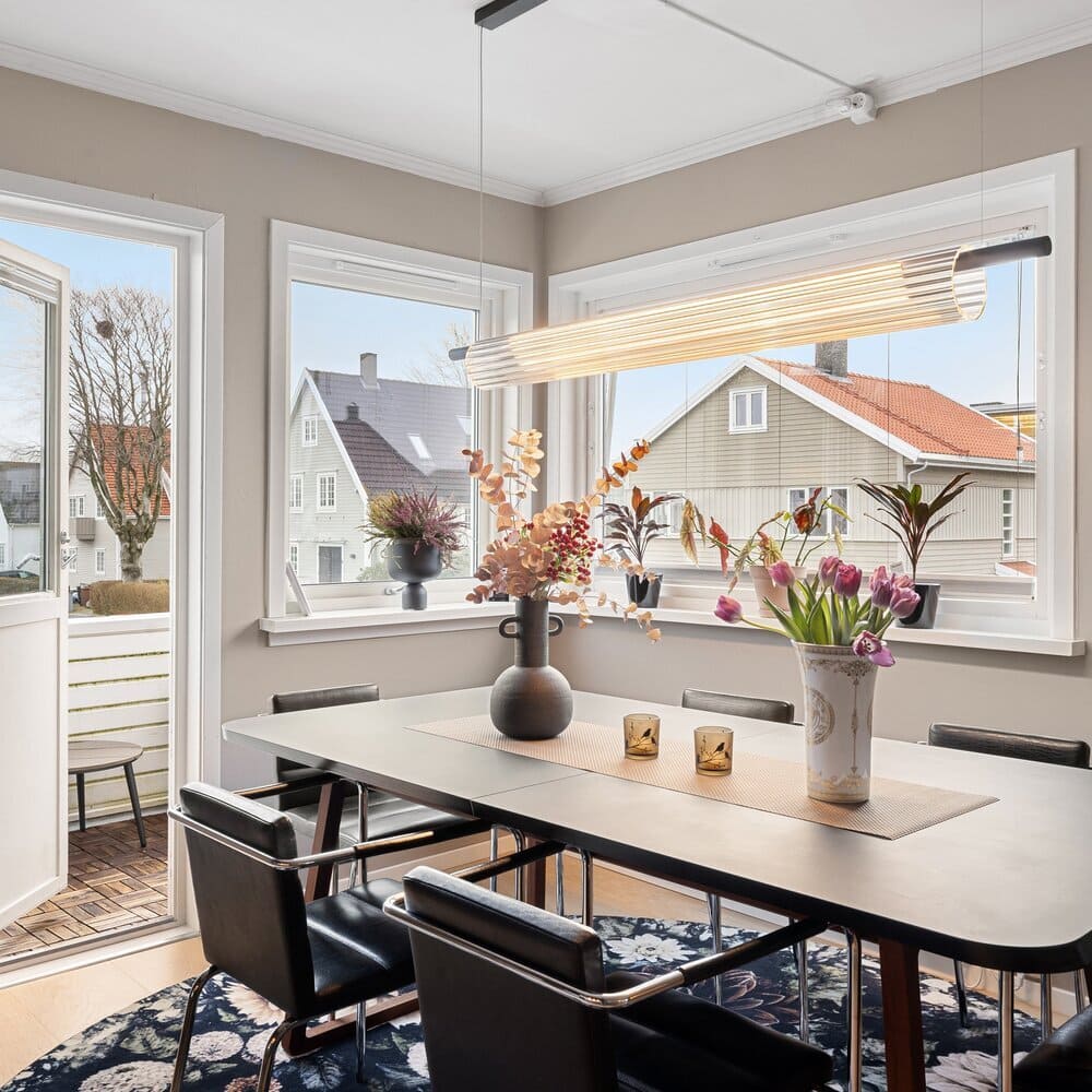 Elegant dining room with modern lighting, bright natural light from large windows, and a stylish setting