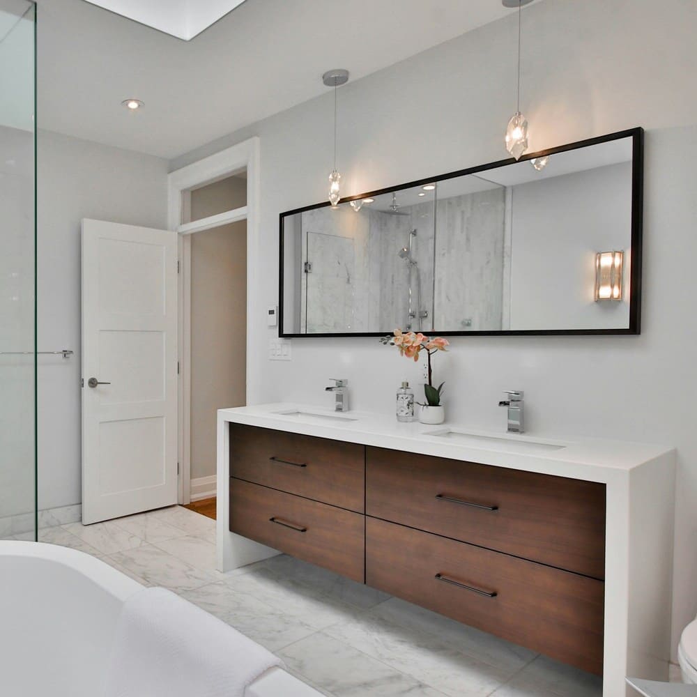 Modern bathroom with clean lighting, featuring a glass shower, twin mirrors, and white tiles