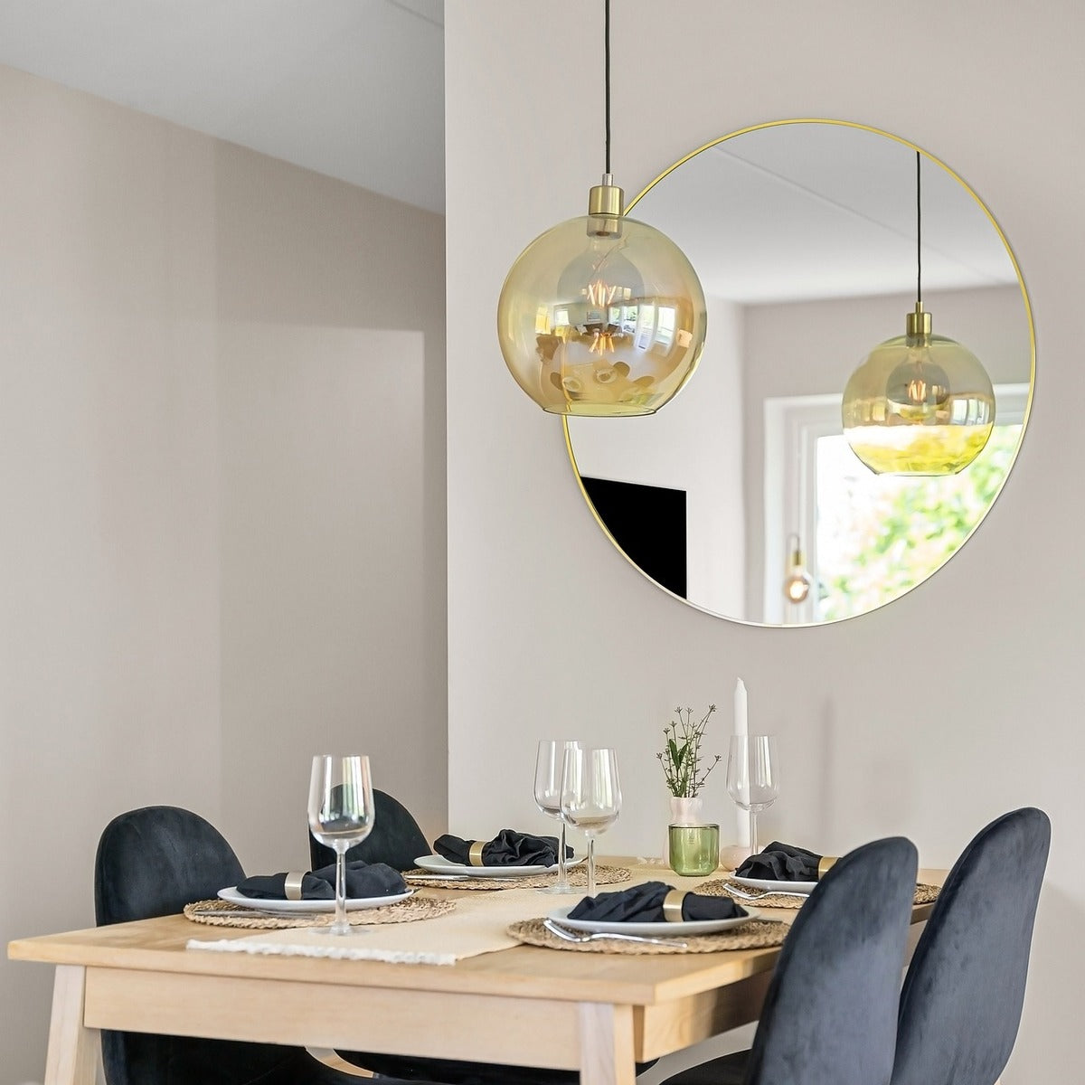 Elegant dining room featuring a round mirror and a pendant light above a well-set dining table