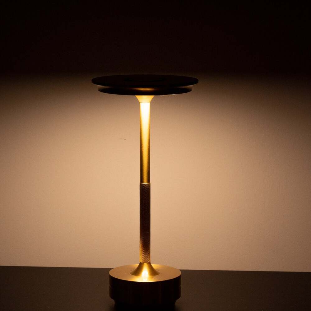 Brass cordless table lamp glowing softly in a dark room, ideal for ambient lighting.