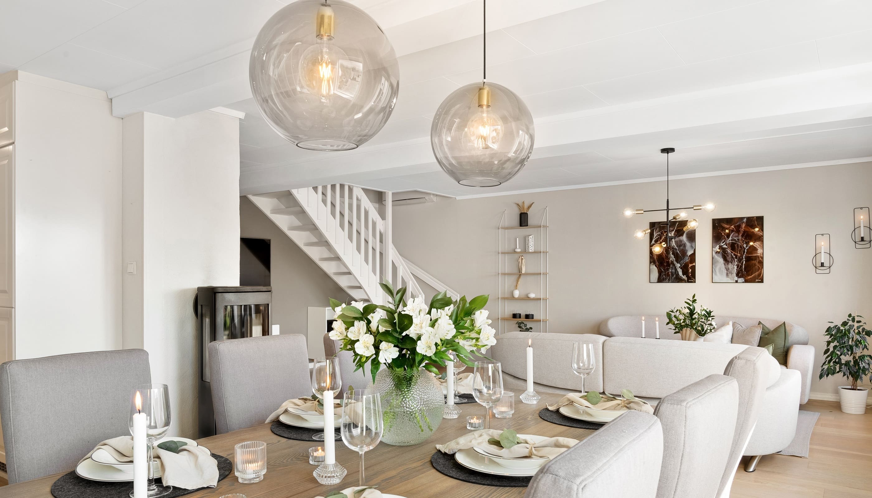 Modern dining room featuring glass pendant lights, a wooden dining table, and elegant table setting