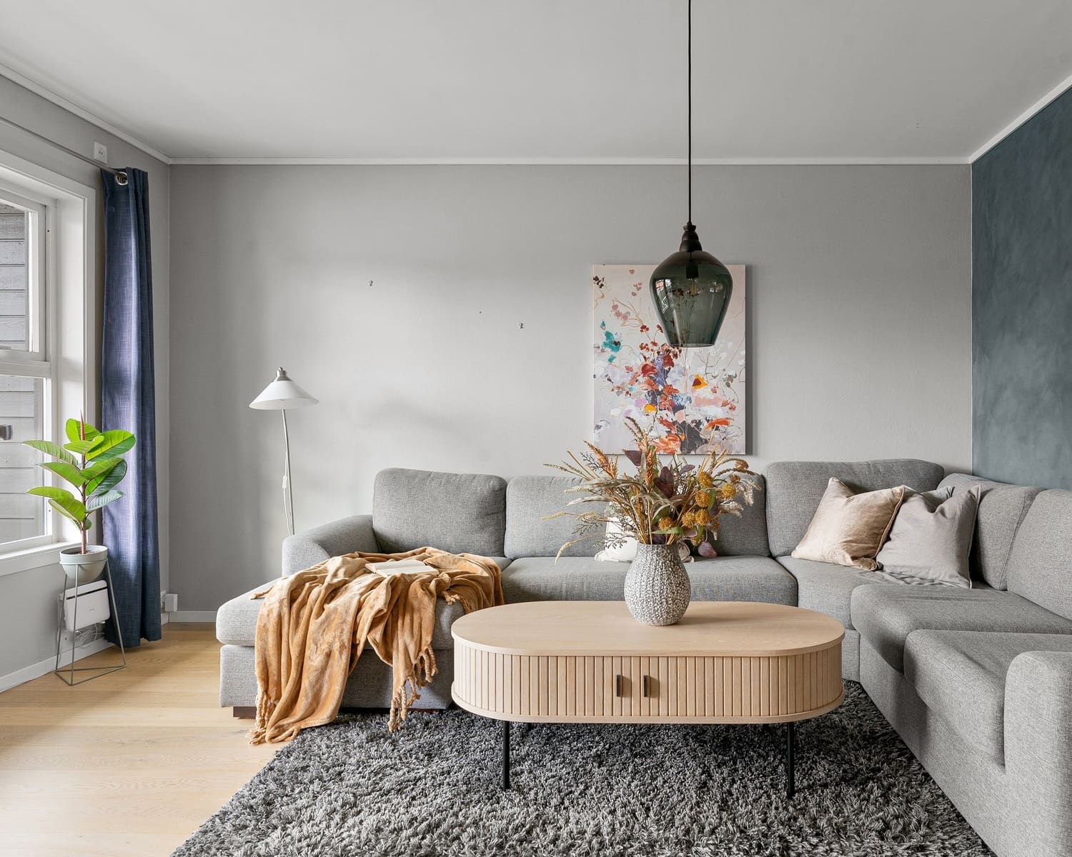 Minimalist living room with gray sofa, wooden coffee table, and fresh greenery. Scandinavian and Modern style.