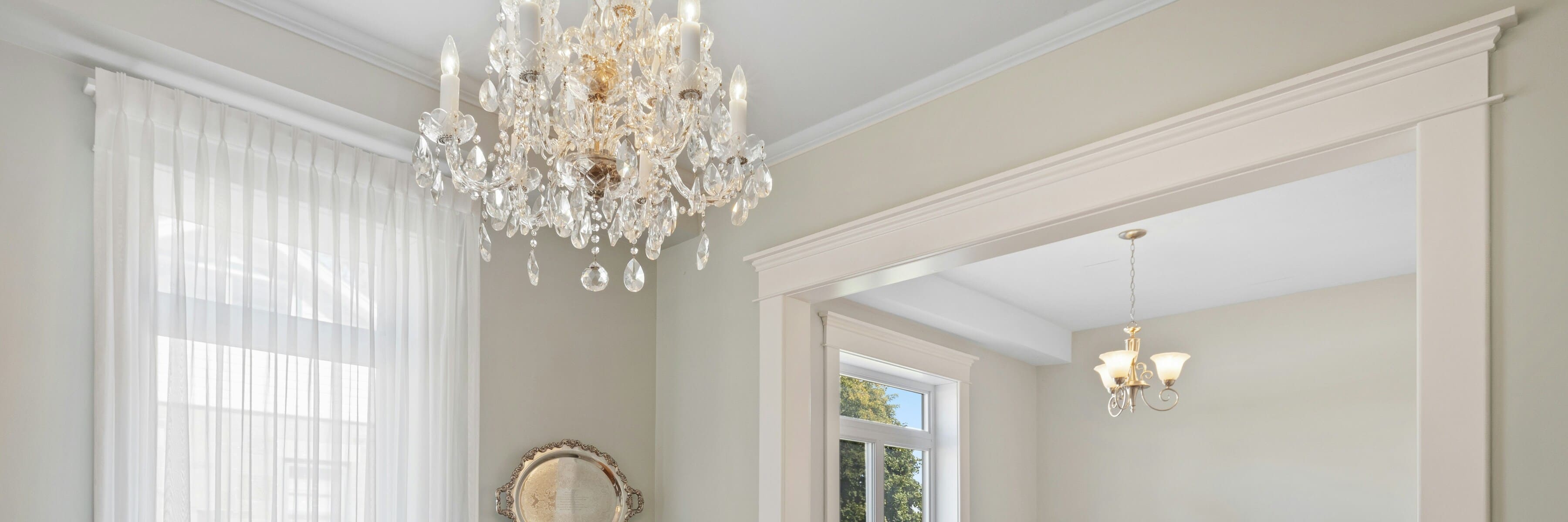 A classic dining room featuring a large crystal chandelier with multiple hanging crystals and intricate detailing, adding a touch of luxury to the space.