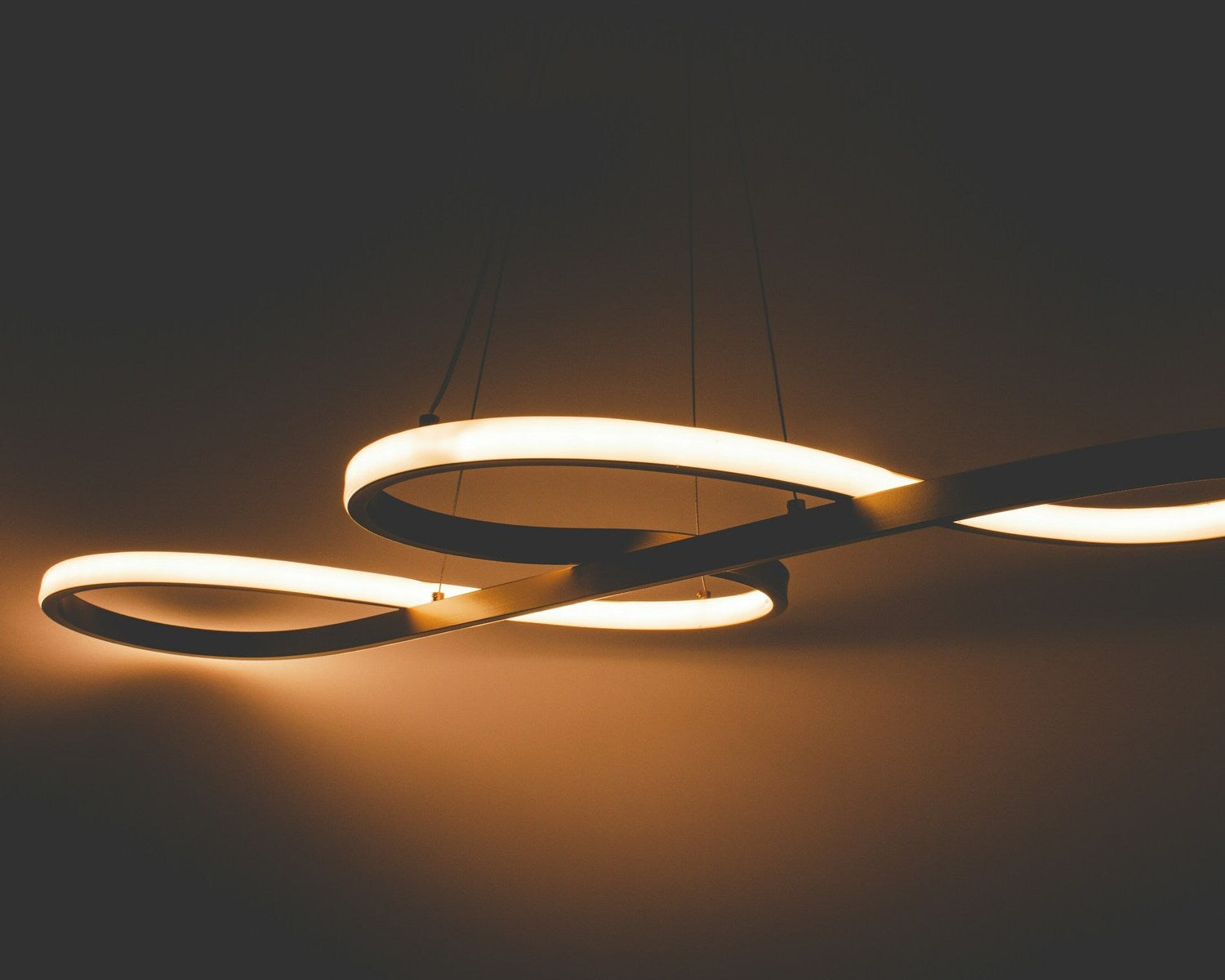 Elegant curved LED pendant light with a minimalist design, providing warm lighting in a stylish modern interior.