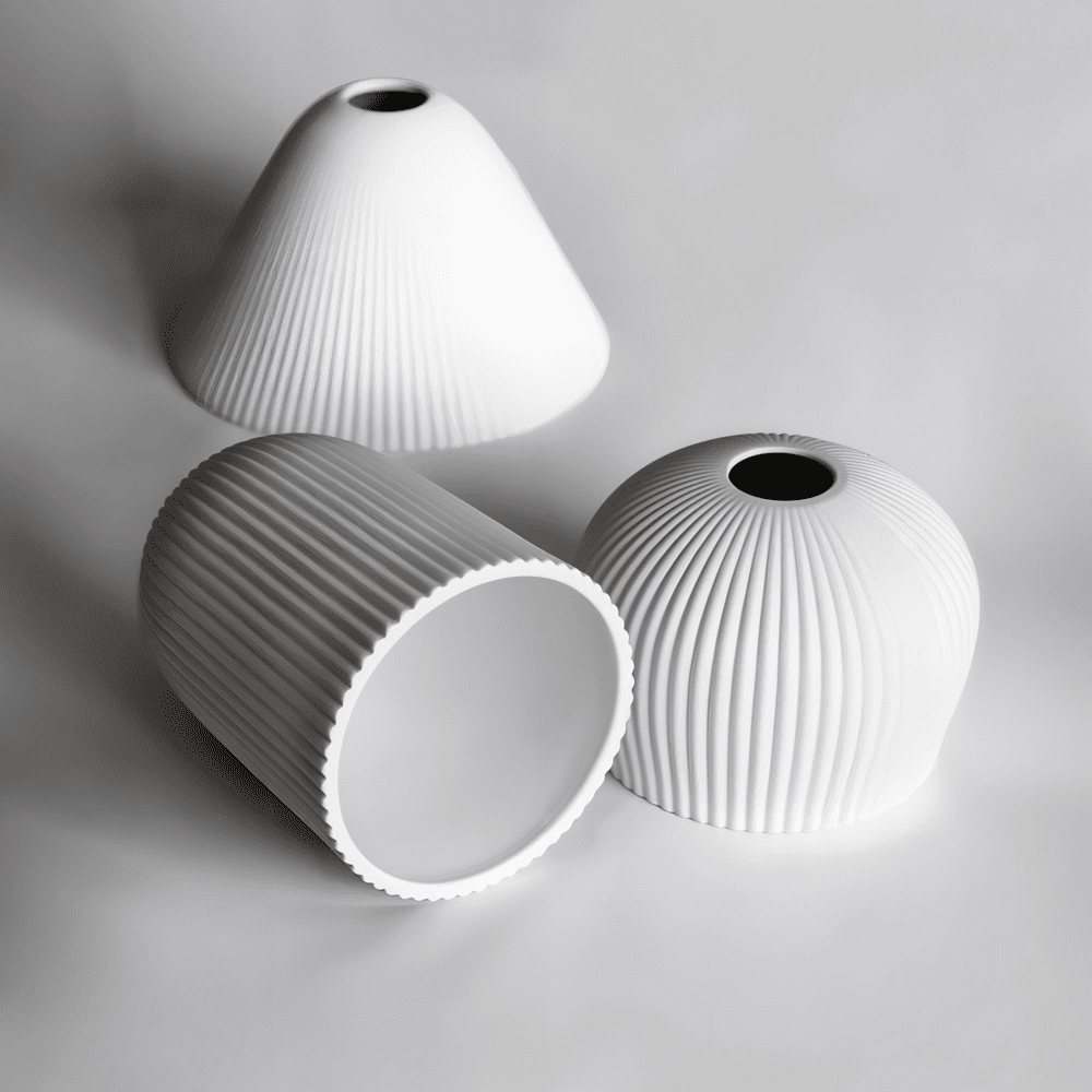 Three minimalist white ceramic lampshades with ribbed textures displayed on a neutral background. The lampshades vary in shapes, showcasing modern design and elegance.