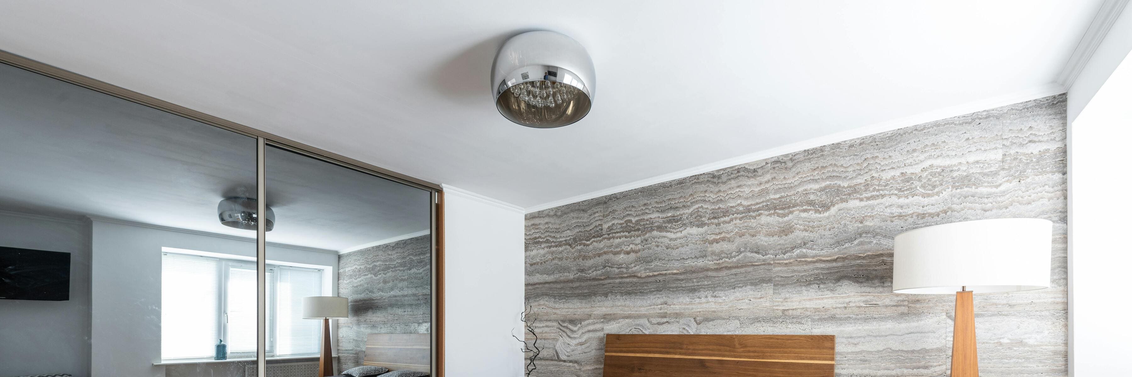 Modern bedroom featuring a sleek crystal flush mount ceiling light and a mirrored wardrobe door.