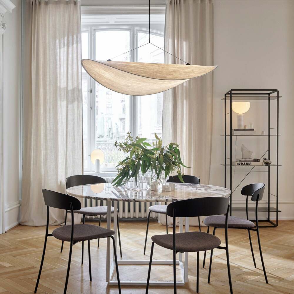 Tense Pendant Light hanging over a dining table in a bright, airy room with large windows.