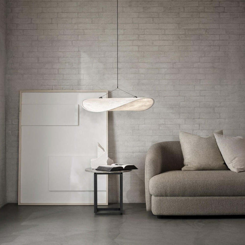 Tense Pendant Light illuminating a cozy corner next to a couch, enhancing the room's decor.